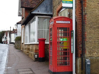 Red telephone box housing defibrillator on a street corner in Watton.