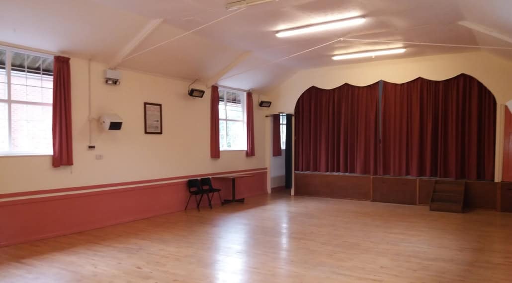 Spacious interior of War Memorial Hall with stage and wooden floor.