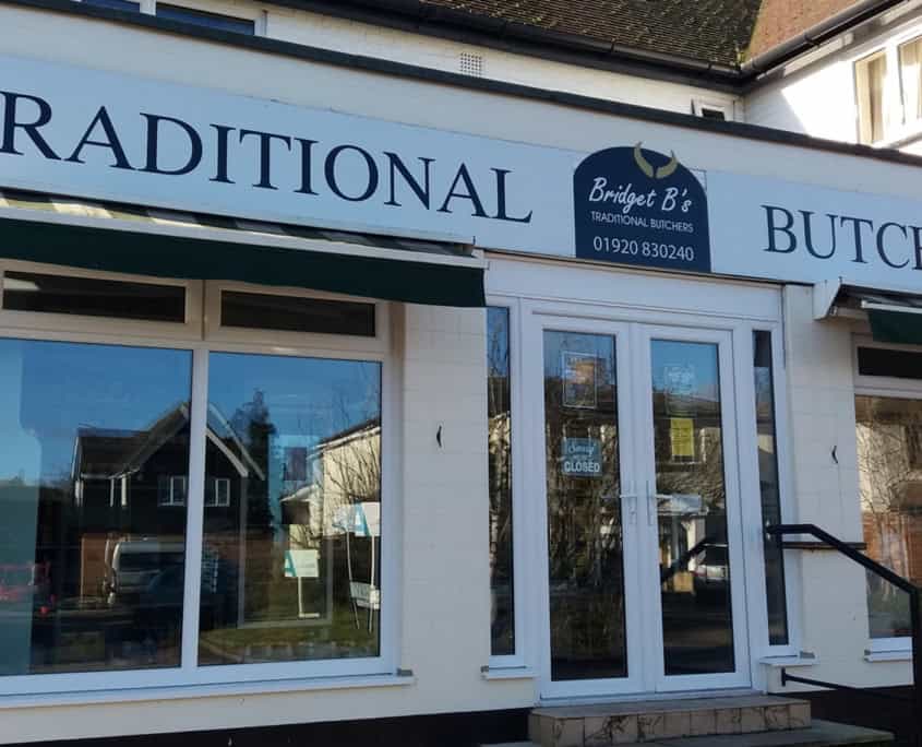 Traditional butchers shop with signage for shops and services.